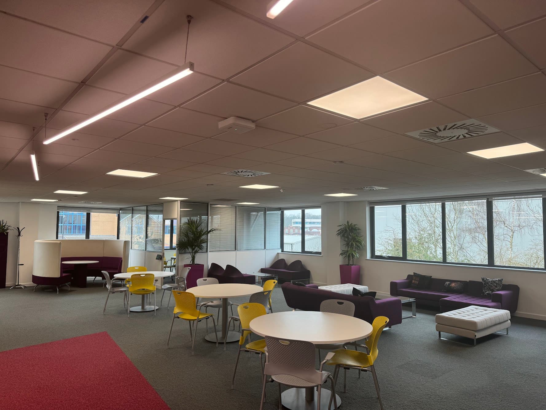 Open-plan breakout and social space at Autodesk's Birmingham premises, showing new LED linear pendant and panel lighting installed throughout the ceiling.