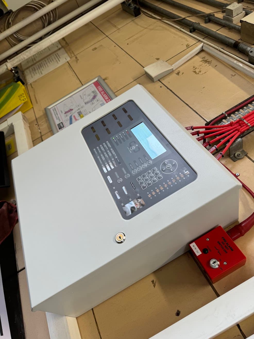 Addressable fire alarm control panel during installation at Erdington Fire Station, shown open with its internal keypad and display visible alongside site cabling.
