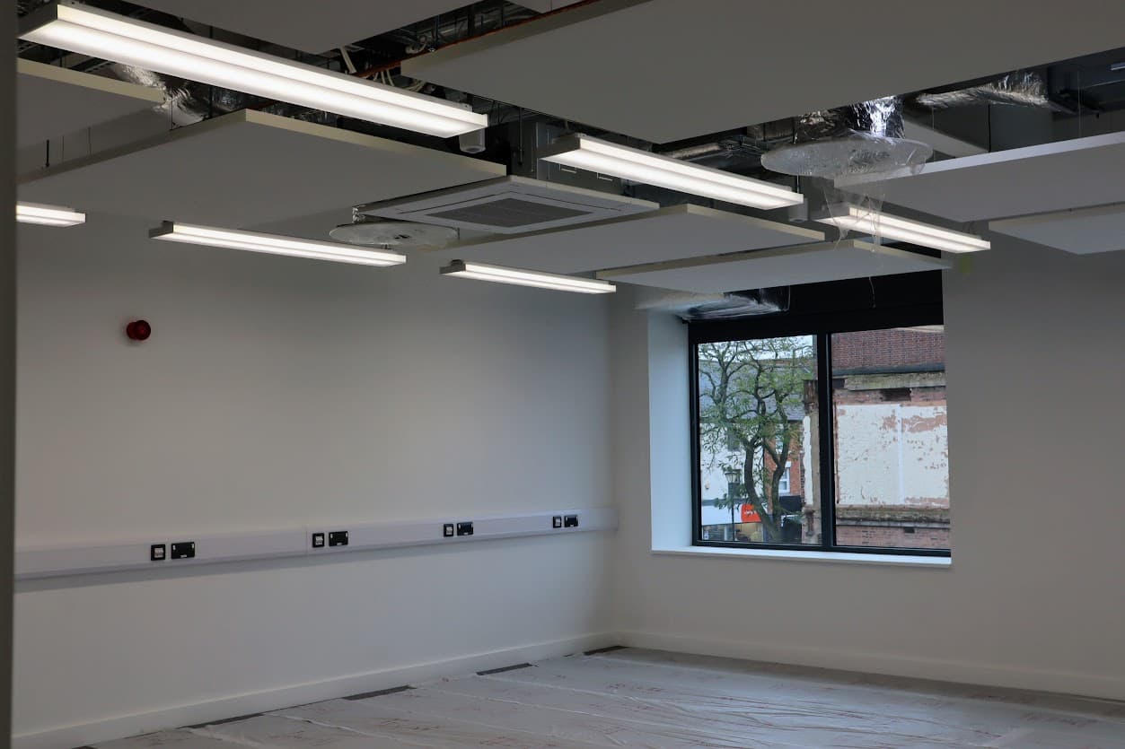 Completed electrical and lighting installation within a teaching space at Nuneaton Digital Skills Centre, including ceiling-mounted lighting, air conditioning and wall-mounted power and data outlets.
