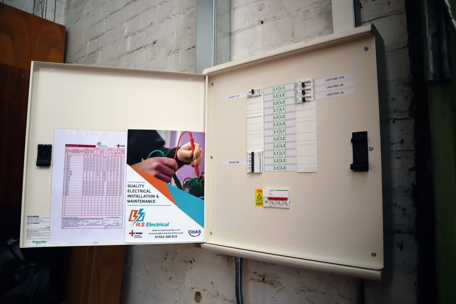 A completed distribution board installed by RS Electrical at ORS's Burton-on-Trent facility, with labelled circuits and RS Electrical documentation fixed to the inside of the enclosure door.