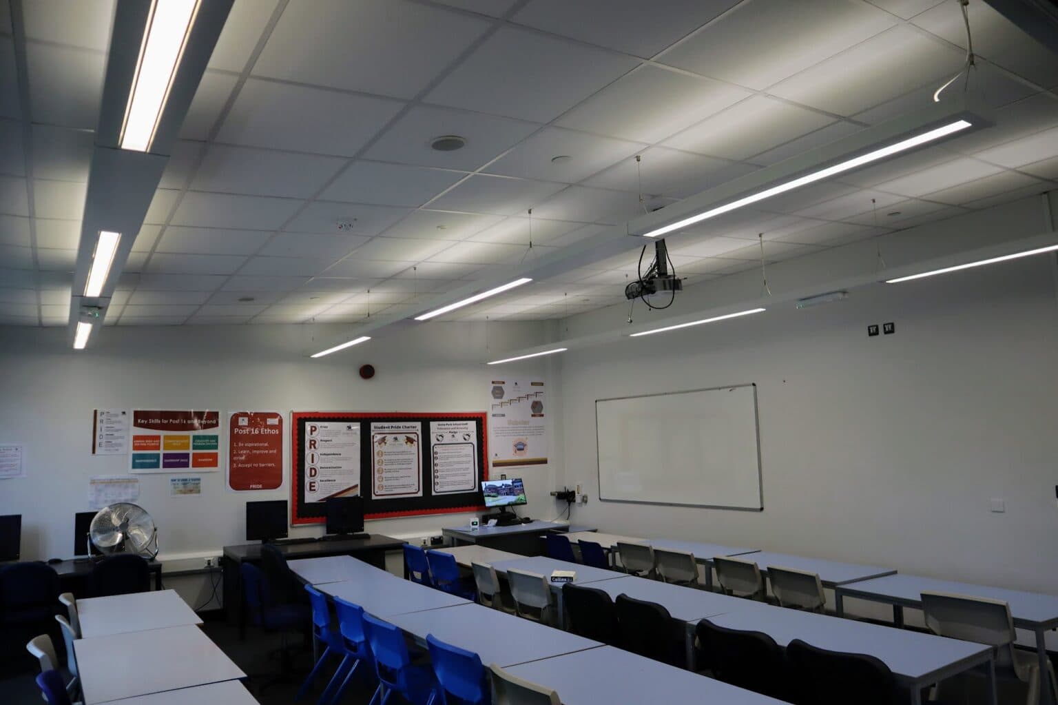 A classroom at Stoke Park School fitted with new LED linear lighting, showing rows of desks and chairs beneath the upgraded ceiling installation.